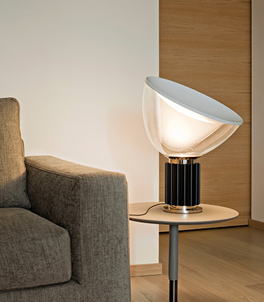 Contemporary designer lamp that provides soft ambient lighting next to a modern sofa